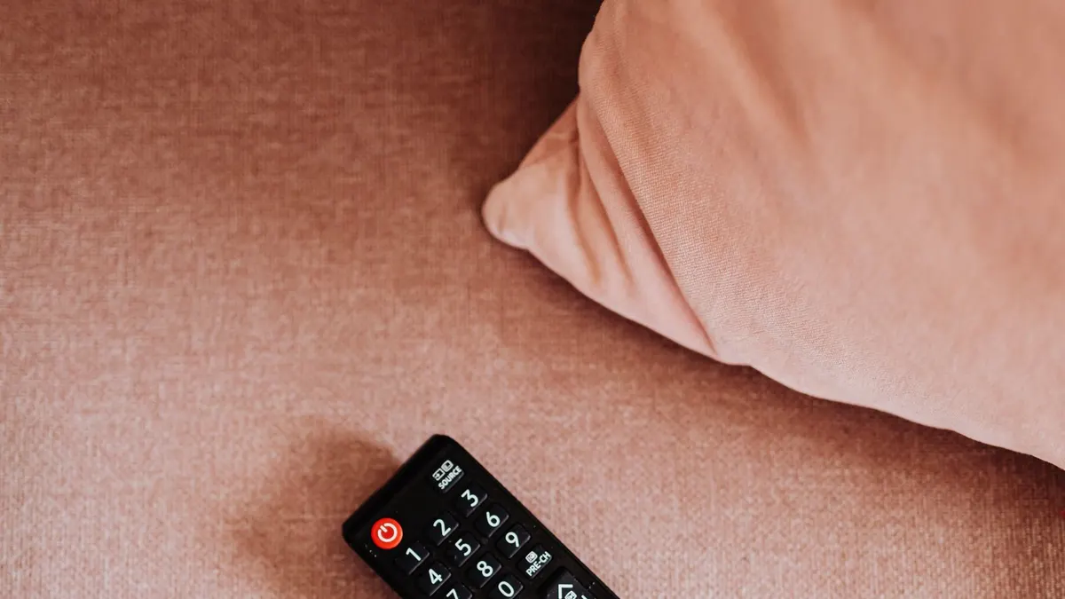 Television kaukosäätimet vaaleanpunaisella kankaalla.