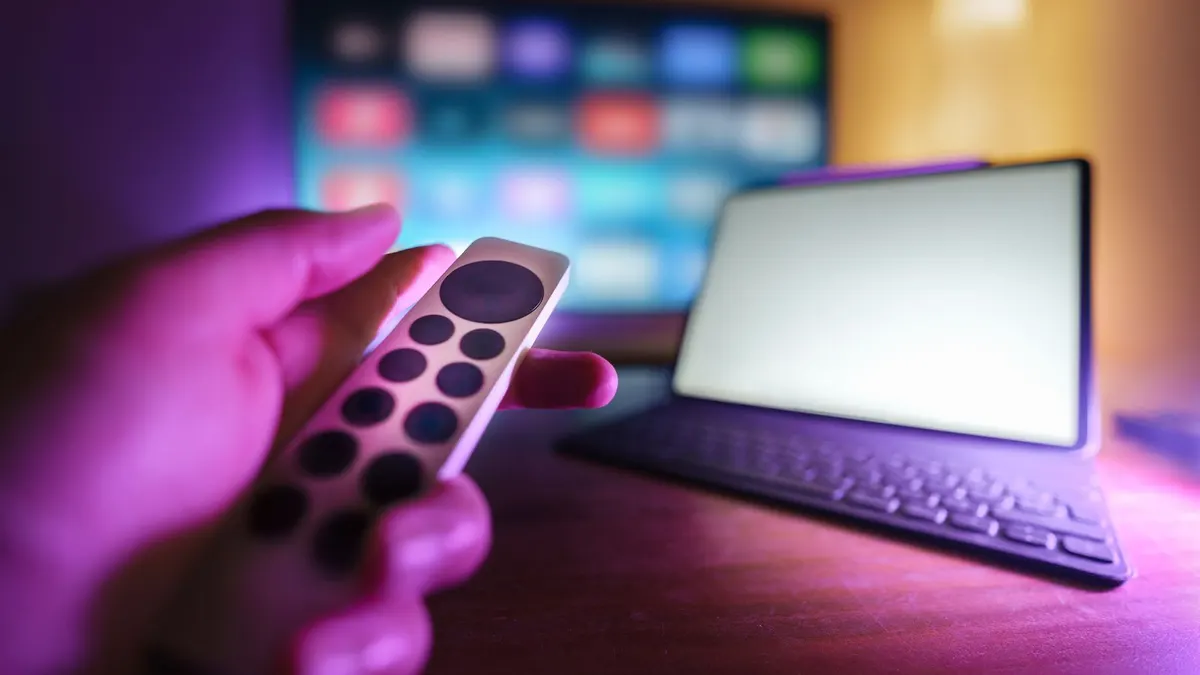 Kaukosäädin, televisio ja kannettava tietokone samassa katseluympäristössä.