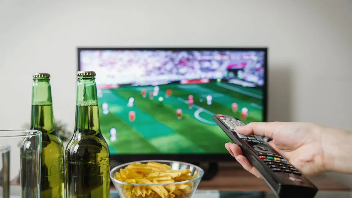 Jalkapallo-ottelun katselua televisiosta kaukosäätimen avulla.